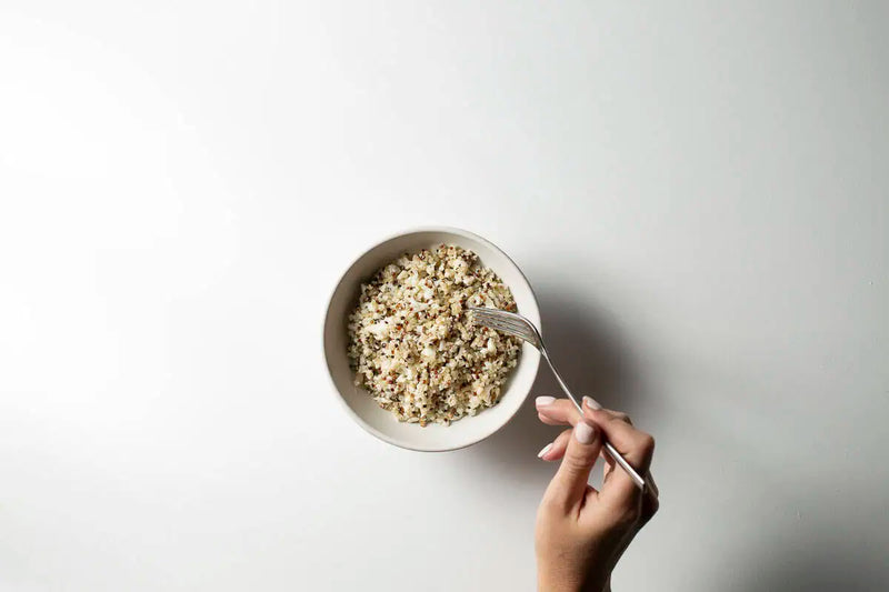 Grain-based cereal snack served in a small white bowl with a fork on a clean white background, viewed from above