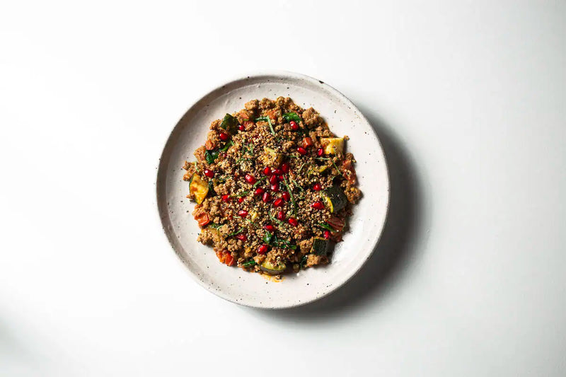 Quinoa and grain salad served on a speckled off-white ceramic plate against a clean white background